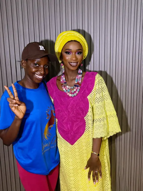 A student making a peace sign beside a finished makeup look with a yellow headwrap