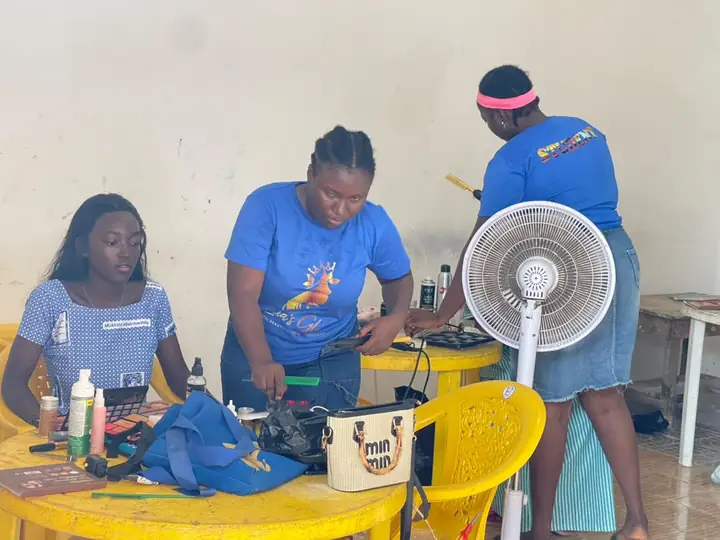 Students practising makeup and hair in blue Licia's Glow shirts, one with STUDENT printed on the back